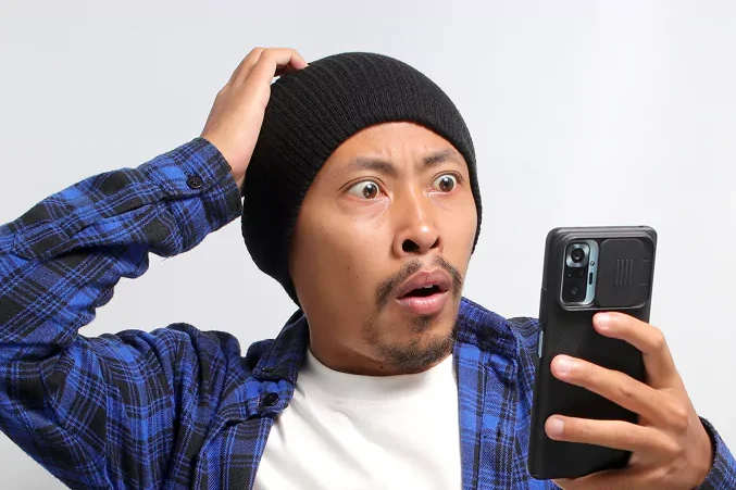 man looking at his phone shocked